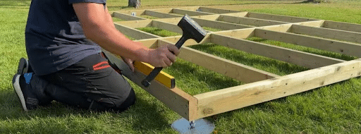 man installing summerhouse frame and measuring to balance