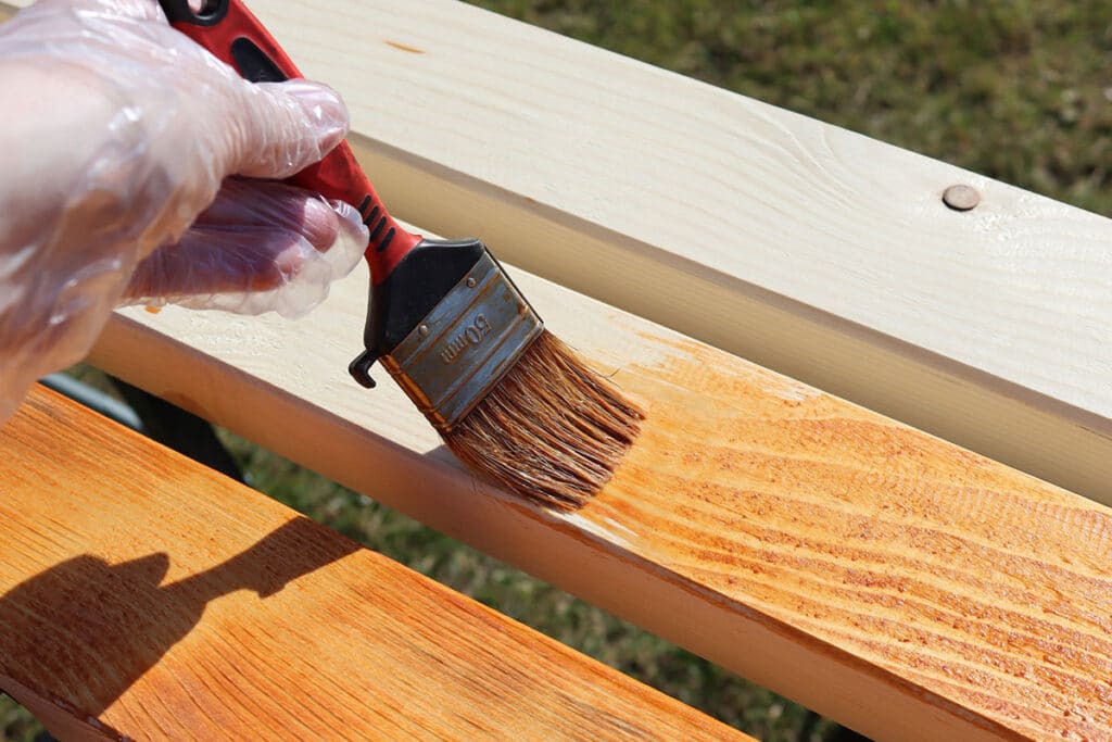 painting a wooden beam with brown varnish